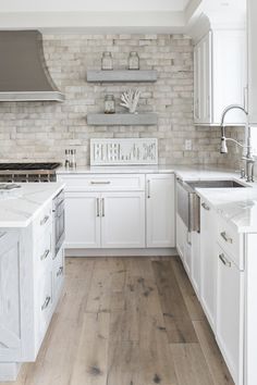 a kitchen with white cabinets and wood floors