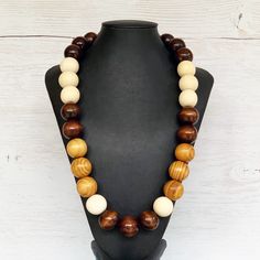 This colorful wood bead necklace was hand beaded using a mix of large 25mm round dark brown, tan, and beige wooden beads in a modern color block design. The necklace measures approximately 28 inches in length and is fastened with a silver clasp. The end result is a cool bohemian piece that fits in perfectly with almost any outfit!  Perfect for any gender.  Length can be adjusted if needed - just ask! Wood represents a sense of earthiness, spirituality, creativity, liberty, prosperity, health, an Adjustable Brown Beaded Necklace, Adjustable Brown Beaded Round Necklace, Adjustable Brown Round Beaded Necklace, Adjustable Round Brown Beaded Necklace, Brown Necklaces With Polished Beads, Handmade Brown Beaded Necklaces, Brown Polished Bead Round Necklaces, Earthy Brown Necklace With Large Beads, Brown Polished Beads Round Necklace