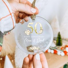 a person holding up a 50th anniversary ornament