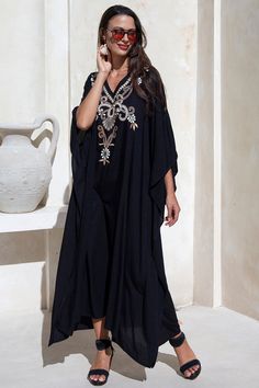 Add a tribal twist to your beach time in this black and gold summer maxi swimwear cover up. Zigzag embroidery adds a spicy accent to this long beach caftan, with a casual vacation vibe and a loose flowy fit that works beautifully on plus sizes. It offers great sun coverage, and is so easy to wear for cruises, lounging, vacation or relaxing days at the beach. Back From Bali is dedicated to creating beautiful, quality clothing with a heart. All of our items are crafted, sewn and painted by hand in Bali, by local artists and women who own small home businesses. For over 20 years, we have nurtured fair, honest and caring relationships with our artisans and their families – so you can feel as good about wearing our products as they feel about making them. Make waves in this black summer maxi sw Embroidered Kaftan For Beach Cover-up, Summer Vacation Embroidered Maxi Dress, Embroidered Maxi Dress For Summer Vacation, Resort Festival V-neck Kaftan, Embroidered Beachwear Maxi Dress For Summer, Summer Beachwear Embroidered Maxi Dress, Summer Embroidered Beachwear Maxi Dress, Embroidered Long Maxi Dress As Beach Cover-up, Bohemian Embroidered Cover-up For Vacation