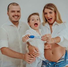 a man and woman holding a child with an electric toothbrush