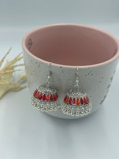 These silver jhumka earrings are a perfect expression of your unique style and personality. They exude a fiery charm and exuberance, making them a perfect choice for those who love bold and vibrant jewelry. Wear them to make a statement, stand out from the crowd, and add a touch of elegance and flair to any outfit. Indulge in the allure of silver jhumka earrings with red and orange hues, available exclusively in our collection. Order now and adorn yourself with the beauty and vibrancy of these exquisite earrings that are sure to become a cherished addition to your jewelry collection! These jhumka earrings are lightweight and comfortable to wear, making them ideal for special occasions, festivals, or everyday wear. They are crafted with high-quality materials to ensure durability and longev Vibrant Jewelry, Silver Jhumka Earrings, Orange Hues, Red And Orange, Pretty Packaging, Jhumka Earrings, Jewelry Earrings Dangle, My Jewellery, Unique Style