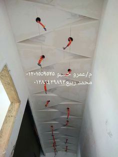 some people are hanging upside down from the ceiling in an empty room with white walls