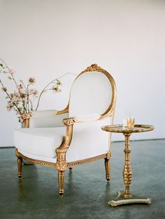 a white chair sitting next to a small table with a candle on top of it