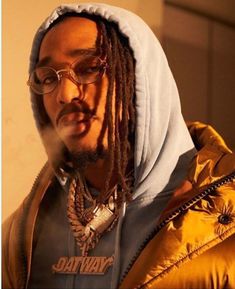 a man with dreadlocks wearing a hoodie and glasses looking off to the side