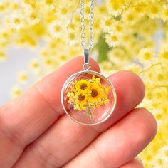 A beautiful sunflower themed pendant encased in a sterling silver round frame. The pendant is the perfect way to send someone special a bunch of bright, beautiful sunflowers. The sunflower pendant features a tiny, bunch of sunflowers, design surrounded by real pressed Queen Anne's Lace flowers preserved in resin.  Please note that the sunflowers themselves are not real pressed flowers. The pendant measures approximately 20mm in width and height excluding the bail.  The pendant is further decorat Sunflower Design Floral Jewelry, Yellow Sunflower Design Jewelry Gift, Yellow Flower Jewelry For Mother's Day, Sunflower Design Jewelry For Mother's Day, Yellow Round Jewelry For Mother's Day, Yellow Round Sunflower Jewelry, Yellow Flower Jewelry For Anniversary, Mother's Day Sunflower Design Jewelry, Yellow Flower Shaped Jewelry With Sunflower Print