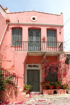 an old pink building with flowers on the ground