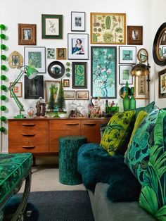 a living room filled with lots of green furniture and pictures on the wall above it