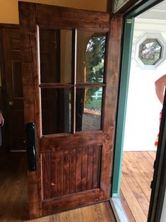 a person standing in front of a wooden door with glass panes on the side