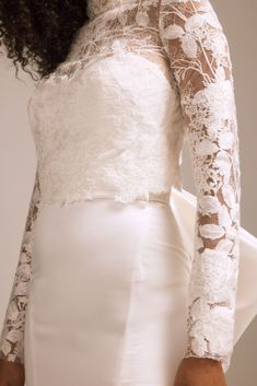 a woman in a white dress with long sleeves and lace on her arms is posing for the camera