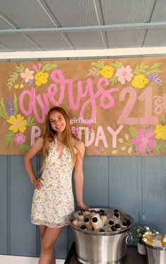 a woman standing in front of a metal bucket filled with ice cream and toppings