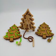 three wooden christmas trees are next to a pair of ear buds and a green string