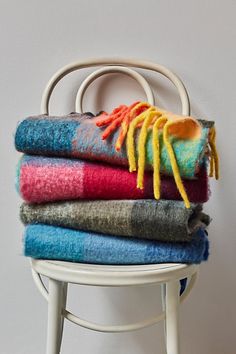 a stack of colorful towels sitting on top of a white chair next to a wall