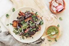 a white plate topped with meat and veggies next to a bowl of salsa