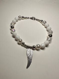 "This is a beautiful OOAK handmade beaded bracelet with an Angel wing charm. The pearl beads really make the silver and clear beads shine! Very pretty white and silver color with  clear beads for accent on a stretchy elastic but has a clasp as well. Also features an Angel wing charm. Will fit a 7\" wrist. Picture taken in different lighting to show how it looks under different settings. We offer free shipping on all of our items! If you are interested in a certain color combination, please send Silver Beaded Pearl Stretch Bracelet, Silver Pearl Stretch Bracelet Gift, Silver Pearl Stretch Bracelet As Gift, Silver Pearl Stretch Bracelet For Gift, White Angel Wings Jewelry As Gift, Angel Accessories, Homemade Necklaces, Angel Bracelet, Spider Necklace