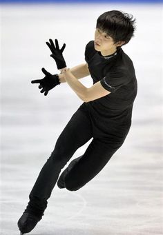 a man in black skating on an ice rink