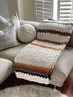 a crocheted blanket sitting on top of a couch next to pillows and a pillow