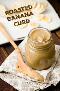 a jar filled with peanut butter sitting on top of a napkin next to sliced bananas