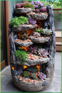 an outdoor planter made out of rocks with succulents and other plants