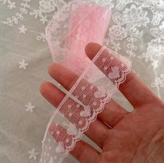 a hand holding a piece of lace on top of a table