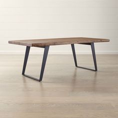 a wooden table sitting on top of a hard wood floor next to a white wall