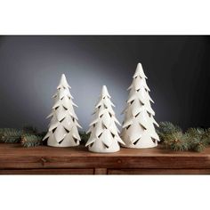 three white ceramic christmas trees sitting on top of a wooden table