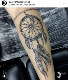 a woman's leg with a tattoo that has a dream catcher and beads on it