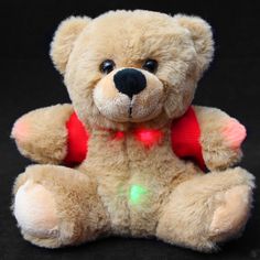 a teddy bear with a red heart on it's chest sitting in front of a black background