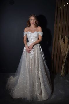 a woman in a wedding dress standing next to a wooden wall with her hands on her hips