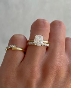 a woman's hand with two gold rings on it and a diamond ring in the middle