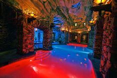 an indoor swimming pool surrounded by stone walls and ceilinging with lights on either side