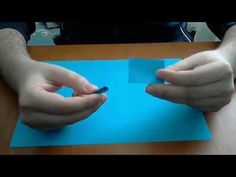 two hands holding something on top of a blue piece of paper