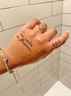 a person's hand with writing on it in front of a white tiled wall