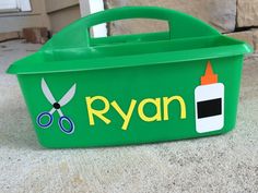 a green plastic container with scissors on the side and name ryan written in yellow letters