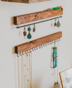 a wooden shelf with jewelry hanging from it's sides next to a wall mounted necklace holder