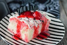 a piece of cake with white and red frosting on it sitting on a striped plate