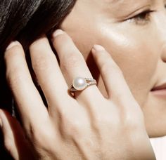 a close up of a person wearing a ring with a pearl on it's middle finger