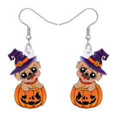 a pair of earrings with a dog wearing a witches hat and sitting on top of a pumpkin