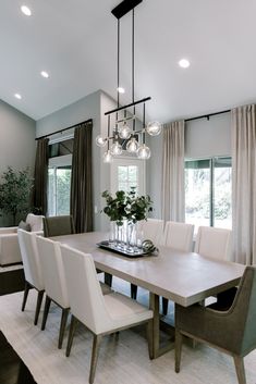 a dining room table with white chairs and lights