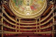 an ornately decorated auditorium with painted ceiling and red velvet seats, is seen from the front