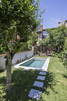 a small pool in the middle of a yard with stepping stones leading up to it