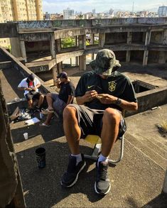 three people sitting on the edge of a building with their cell phones in their hands