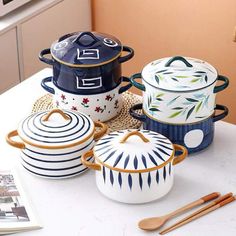 a table topped with pots and pans on top of a white counter next to utensils