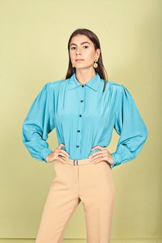 "Gorgeous blouse in an aquamarine blue color with small pointed collar, fitted pleats at the waistline, long sleeves that cuff at the wrists, black buttons from the neck down and pleats at the shoulders. Doesn't stretch and fabric has a shimmery look to it. ➽ brand: Sk & Company ➽ material: poly ➽ condition: great shape! missing the last button ➽ model stats: 32\" 24\" 35\" 5\"7 ➽ size: medium ➽ measures: waist 34\" / pit to pit 44\" / bust 42\" / length 24\" ➽ Apple Branches Vintage applebranch Elegant Luxury Light Blue Blouse, Affordable Non-stretch Blue Blouse, Cheap Non-stretch Blue Blouse, Luxury Light Blue Button-up Top, Luxury Light Blue Fitted Blouse, Luxury Fitted Light Blue Blouse, Luxury Light Blue Blouse Piece For Women, Affordable Blue Collared Blouse, Cheap Blue Workwear Blouse