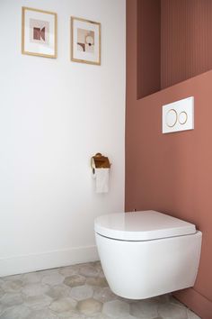 a white toilet sitting next to a pink wall