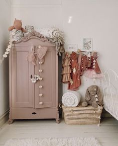 a baby's room with a pink cabinet, teddy bear and other items on the floor