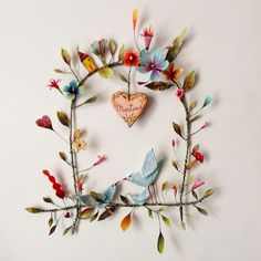 there is a wall decoration made out of paper flowers and leaves with a heart on it