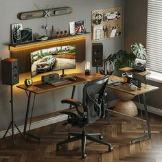 a computer desk with speakers on it in front of a wall mounted tv and bookshelf