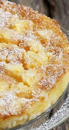 a cake with powdered sugar on top is sitting on a glass platter, ready to be eaten