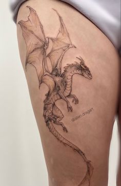 a woman's thigh with a dragon tattoo on it